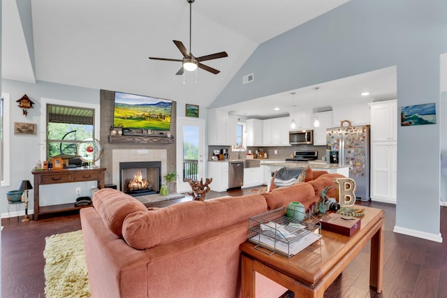 living room with dark hardwood / wood-style flooring, ceiling fan, sink, high vaulted ceiling, and a fireplace