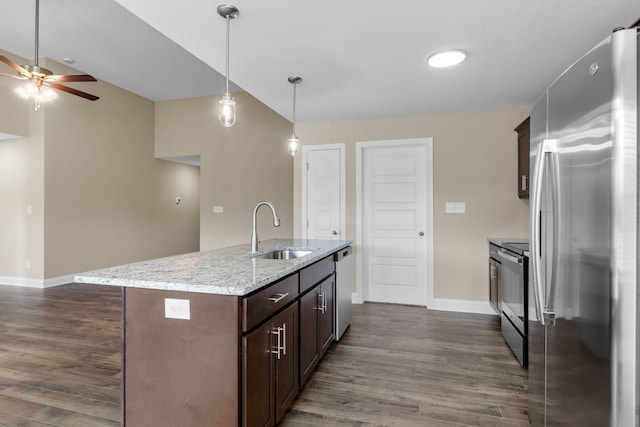 kitchen with a center island with sink, sink, ceiling fan, light stone counters, and stainless steel appliances