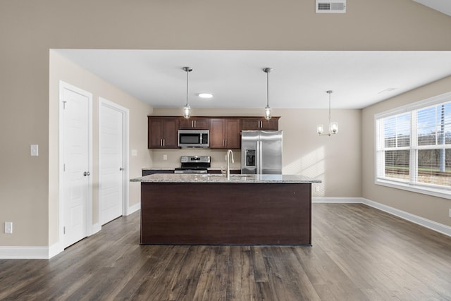 kitchen with light stone counters, dark brown cabinets, stainless steel appliances, sink, and an island with sink