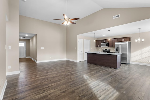 kitchen featuring appliances with stainless steel finishes, dark brown cabinets, dark wood-type flooring, decorative light fixtures, and an island with sink