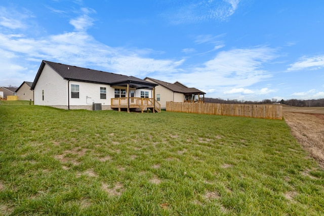 rear view of house with a yard, central AC unit, and a deck