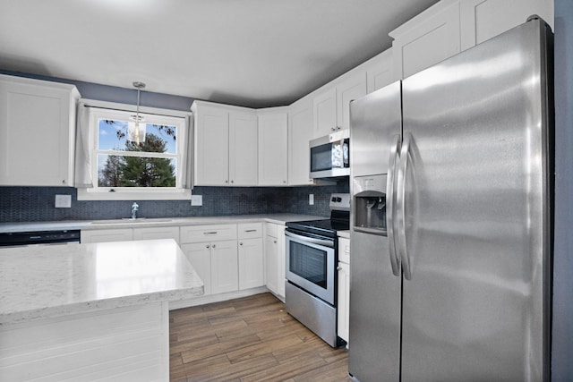 kitchen featuring sink, hanging light fixtures, stainless steel appliances, dark hardwood / wood-style floors, and backsplash