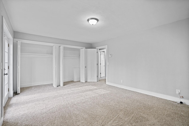 unfurnished bedroom featuring carpet floors and two closets