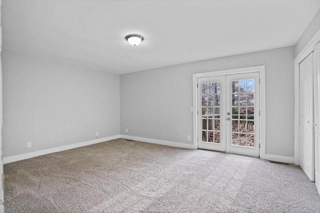 carpeted spare room featuring french doors