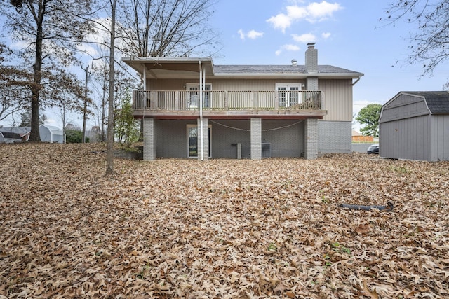 rear view of house featuring a deck and a storage shed