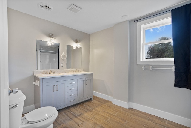 bathroom featuring a shower, wood-type flooring, vanity, and toilet