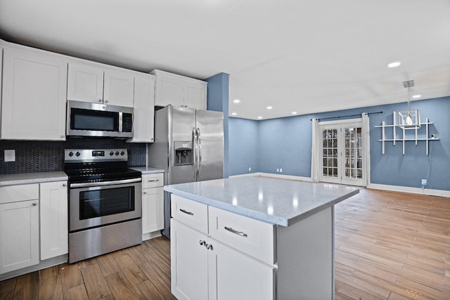 kitchen featuring stainless steel appliances, white cabinetry, and light hardwood / wood-style floors