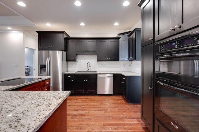 kitchen with backsplash, black appliances, crown molding, sink, and light stone countertops