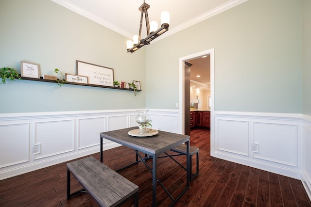 dining area with ornamental molding, a chandelier, wainscoting, dark wood-style floors, and a decorative wall