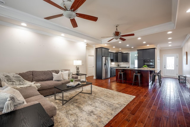 living area featuring ceiling fan, ornamental molding, dark wood-type flooring, recessed lighting, and baseboards