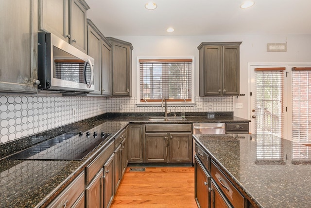 kitchen with tasteful backsplash, sink, dark stone counters, light hardwood / wood-style floors, and stainless steel appliances