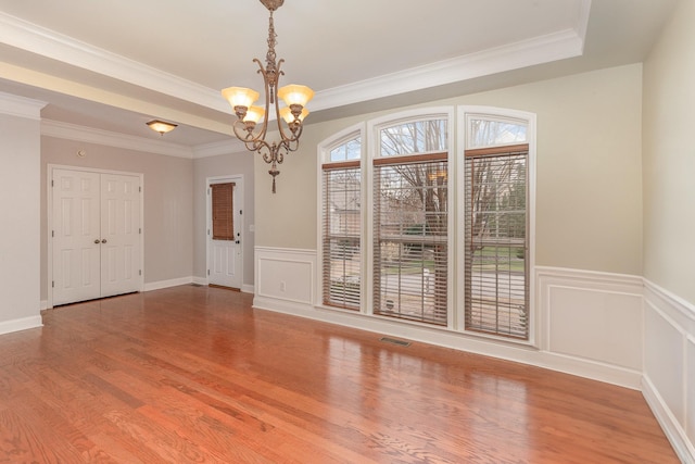 unfurnished room featuring hardwood / wood-style flooring, a tray ceiling, an inviting chandelier, and crown molding