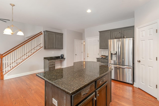 kitchen with light hardwood / wood-style flooring, a kitchen island, dark stone countertops, and stainless steel refrigerator with ice dispenser