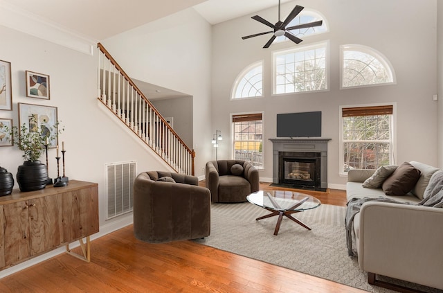 living room with hardwood / wood-style floors, a towering ceiling, a healthy amount of sunlight, and ceiling fan