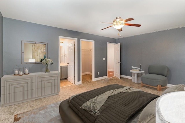 carpeted bedroom featuring ceiling fan, a walk in closet, a closet, and ensuite bath