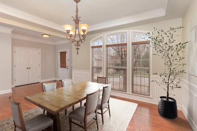 dining room featuring crown molding, hardwood / wood-style floors, a notable chandelier, and a raised ceiling