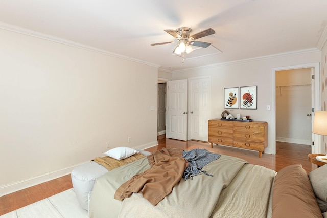 bedroom with crown molding, ceiling fan, a closet, and light wood-type flooring