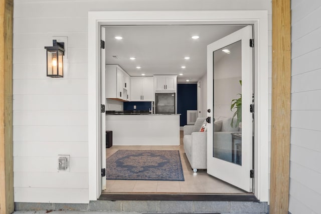 kitchen with white cabinets, black fridge, and light tile patterned floors