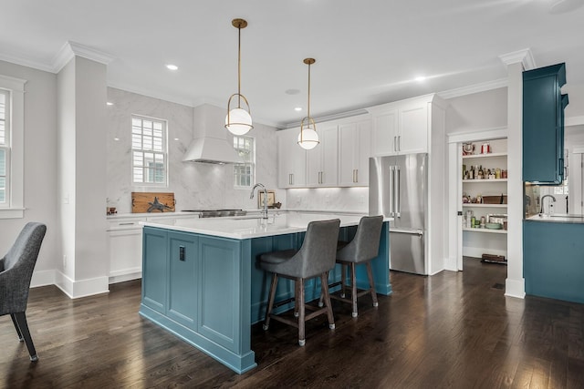 kitchen featuring a center island with sink, hanging light fixtures, dark hardwood / wood-style floors, high quality fridge, and white cabinetry