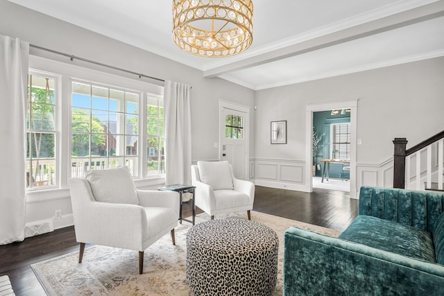 sitting room with crown molding, dark wood-type flooring, a healthy amount of sunlight, and a notable chandelier