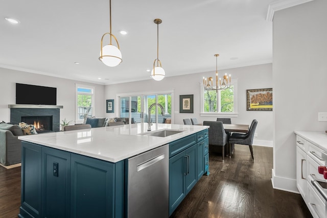 kitchen featuring blue cabinetry, dishwasher, hanging light fixtures, and sink