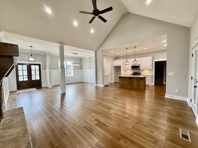 unfurnished living room featuring french doors, high vaulted ceiling, ceiling fan with notable chandelier, and hardwood / wood-style flooring