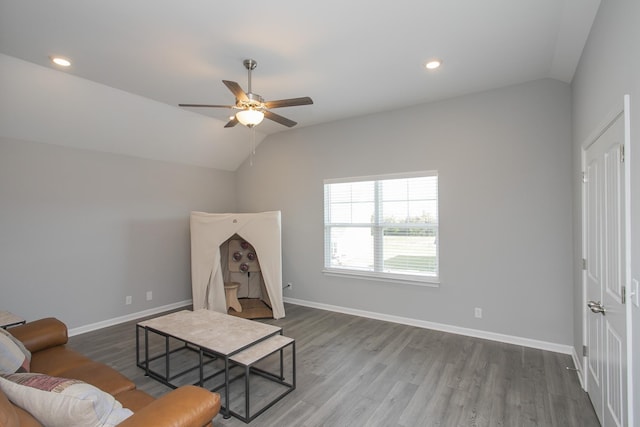 living room featuring ceiling fan, wood-type flooring, and vaulted ceiling