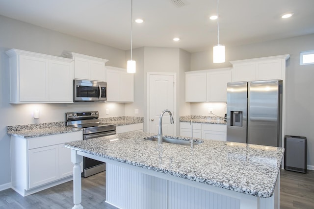 kitchen featuring sink, stainless steel appliances, decorative light fixtures, and a center island with sink