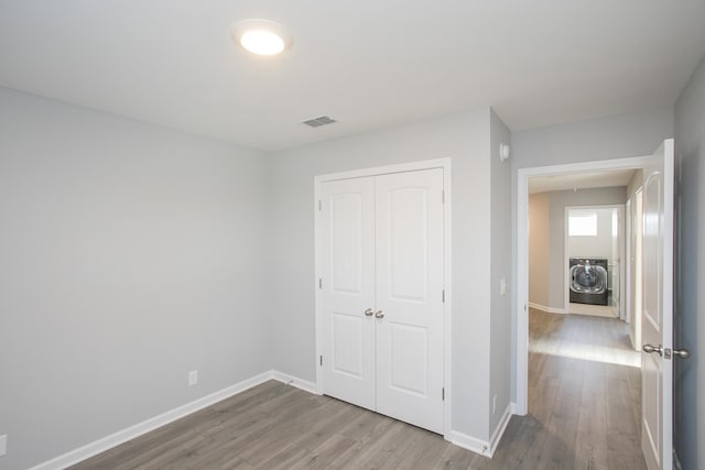 unfurnished bedroom featuring a closet, washer / dryer, and light hardwood / wood-style flooring