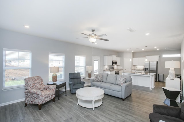 living room with ceiling fan, light hardwood / wood-style flooring, and sink