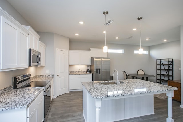 kitchen with appliances with stainless steel finishes, dark hardwood / wood-style flooring, sink, pendant lighting, and a center island with sink