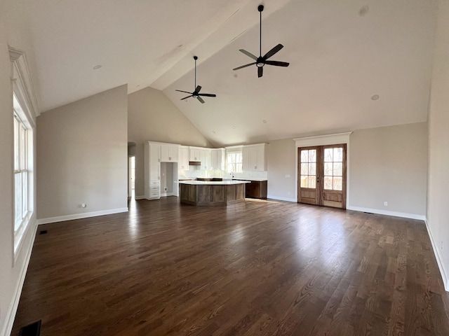 unfurnished living room featuring ceiling fan, french doors, dark wood-type flooring, high vaulted ceiling, and beamed ceiling