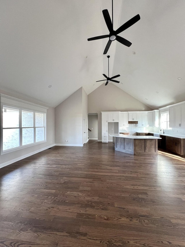 unfurnished living room with ceiling fan, dark hardwood / wood-style flooring, and high vaulted ceiling