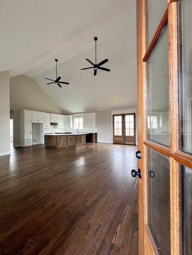 unfurnished living room with ceiling fan, dark wood-type flooring, and high vaulted ceiling