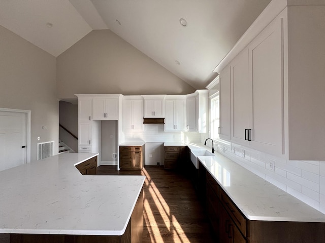 kitchen featuring white cabinets, dark hardwood / wood-style floors, decorative backsplash, and high vaulted ceiling