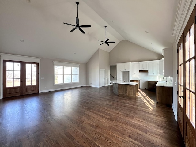 unfurnished living room featuring french doors, ceiling fan, dark wood-type flooring, sink, and high vaulted ceiling