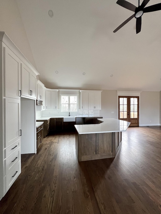 kitchen featuring a large island, dark hardwood / wood-style floors, white cabinetry, and lofted ceiling