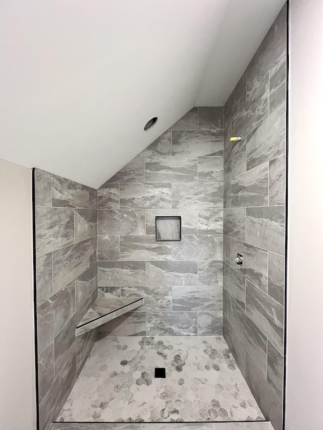 bathroom with vaulted ceiling and tiled shower