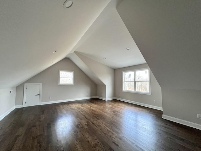 additional living space with dark hardwood / wood-style flooring, vaulted ceiling, and a healthy amount of sunlight