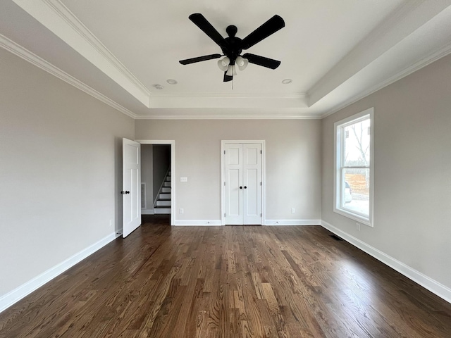 unfurnished bedroom with dark hardwood / wood-style flooring, ceiling fan, a raised ceiling, and crown molding