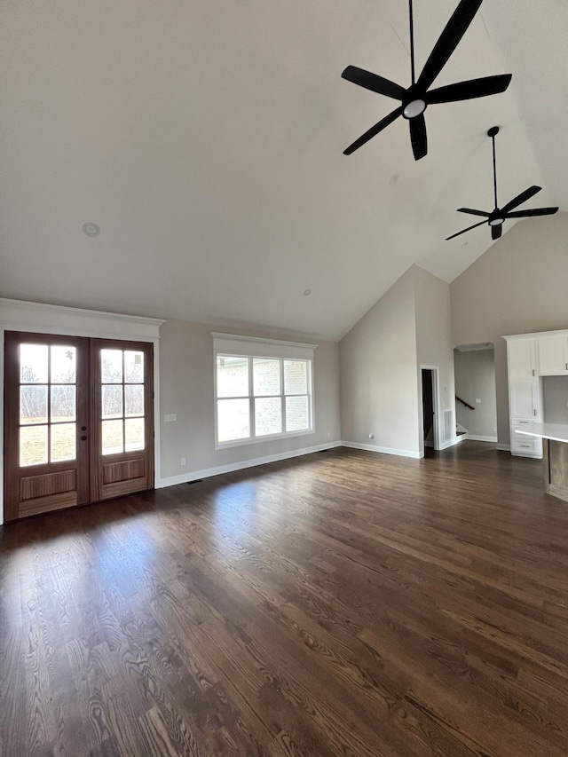 unfurnished living room with plenty of natural light, dark hardwood / wood-style flooring, lofted ceiling, and french doors