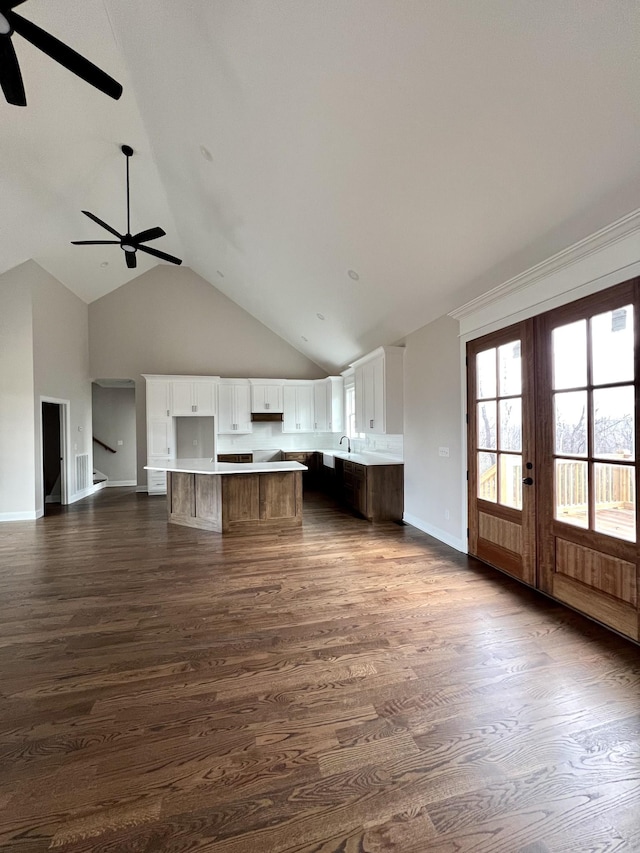 kitchen with ceiling fan, dark wood-type flooring, a kitchen island, high vaulted ceiling, and white cabinets