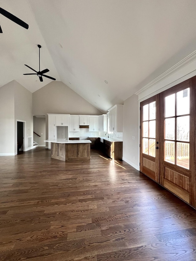 unfurnished living room with ceiling fan, dark hardwood / wood-style flooring, high vaulted ceiling, and french doors