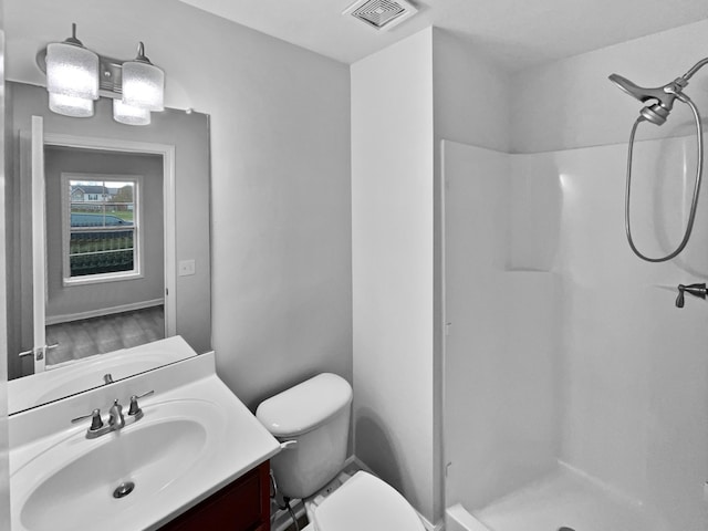 bathroom featuring vanity, toilet, and walk in shower