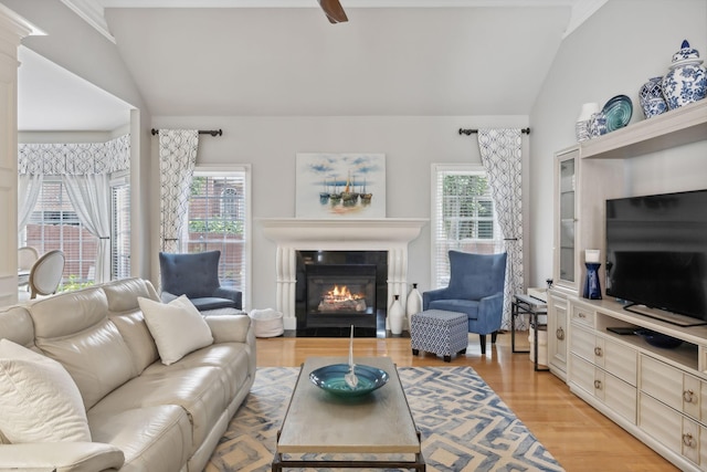 living room featuring lofted ceiling, a fireplace, a wealth of natural light, and light hardwood / wood-style flooring