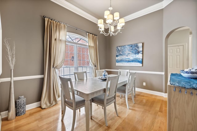 dining room with ornamental molding, hardwood / wood-style flooring, and a notable chandelier