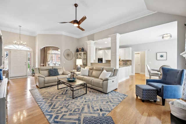 living room featuring lofted ceiling, ceiling fan with notable chandelier, light hardwood / wood-style floors, and crown molding