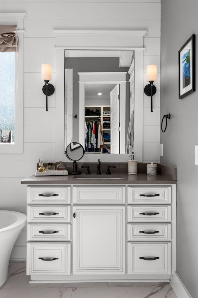 bathroom featuring vanity, a bath, and wood walls