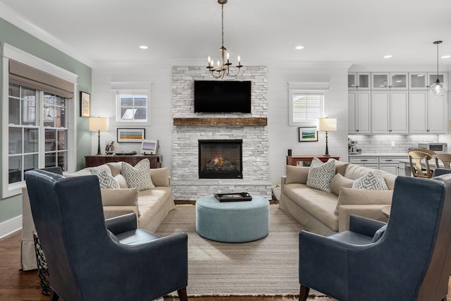 living room with hardwood / wood-style flooring, crown molding, a chandelier, and a fireplace