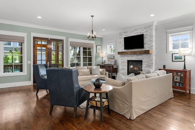 living room featuring a healthy amount of sunlight, dark wood-type flooring, an inviting chandelier, and a fireplace